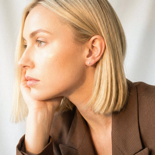 Woman with blonde hair wearing a brown blazer against a neutral background