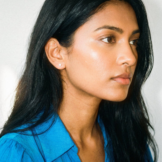 Woman with long dark hair wearing a blue shirt against a neutral background