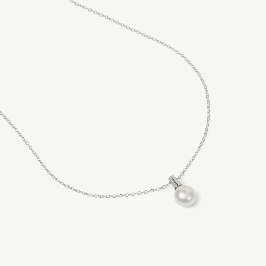 Pearl necklace on a thin chain against a light gray background