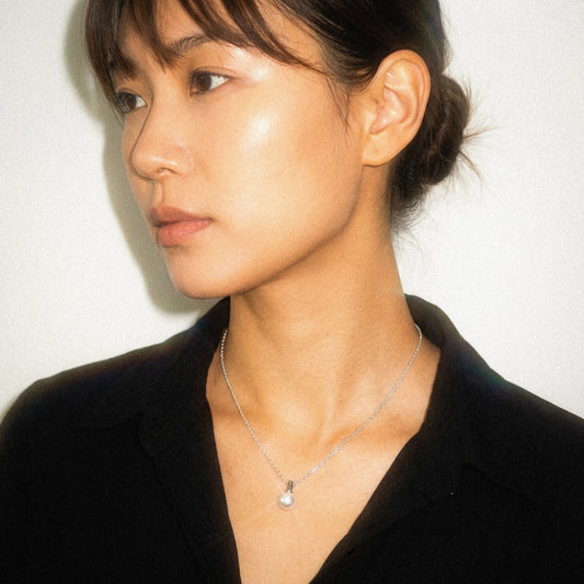Woman wearing a black blazer and silver necklace against a plain background
