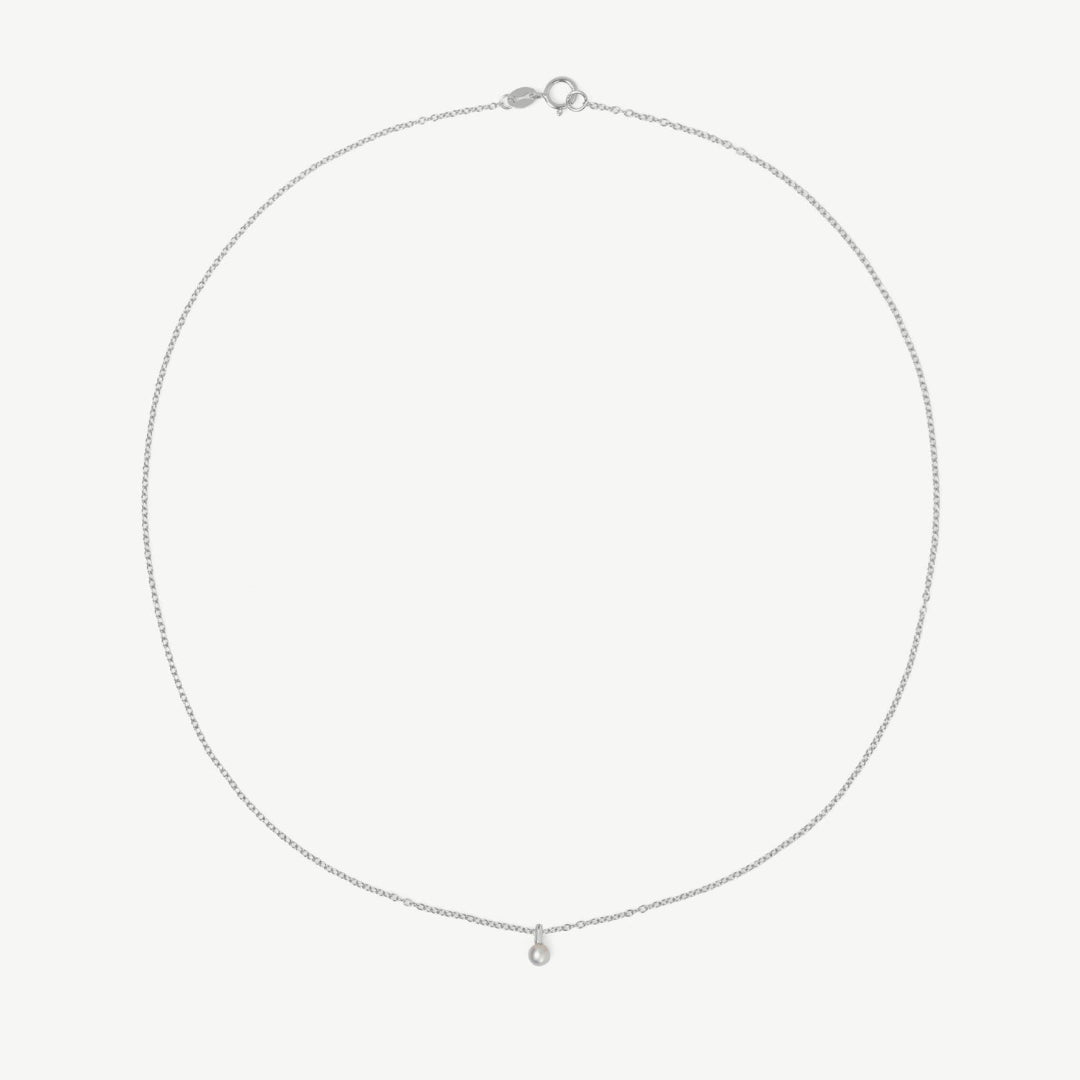 Silver necklace with a small pendant on a light gray background
