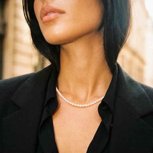 Close-up of a person wearing a pearl necklace with a blurred background