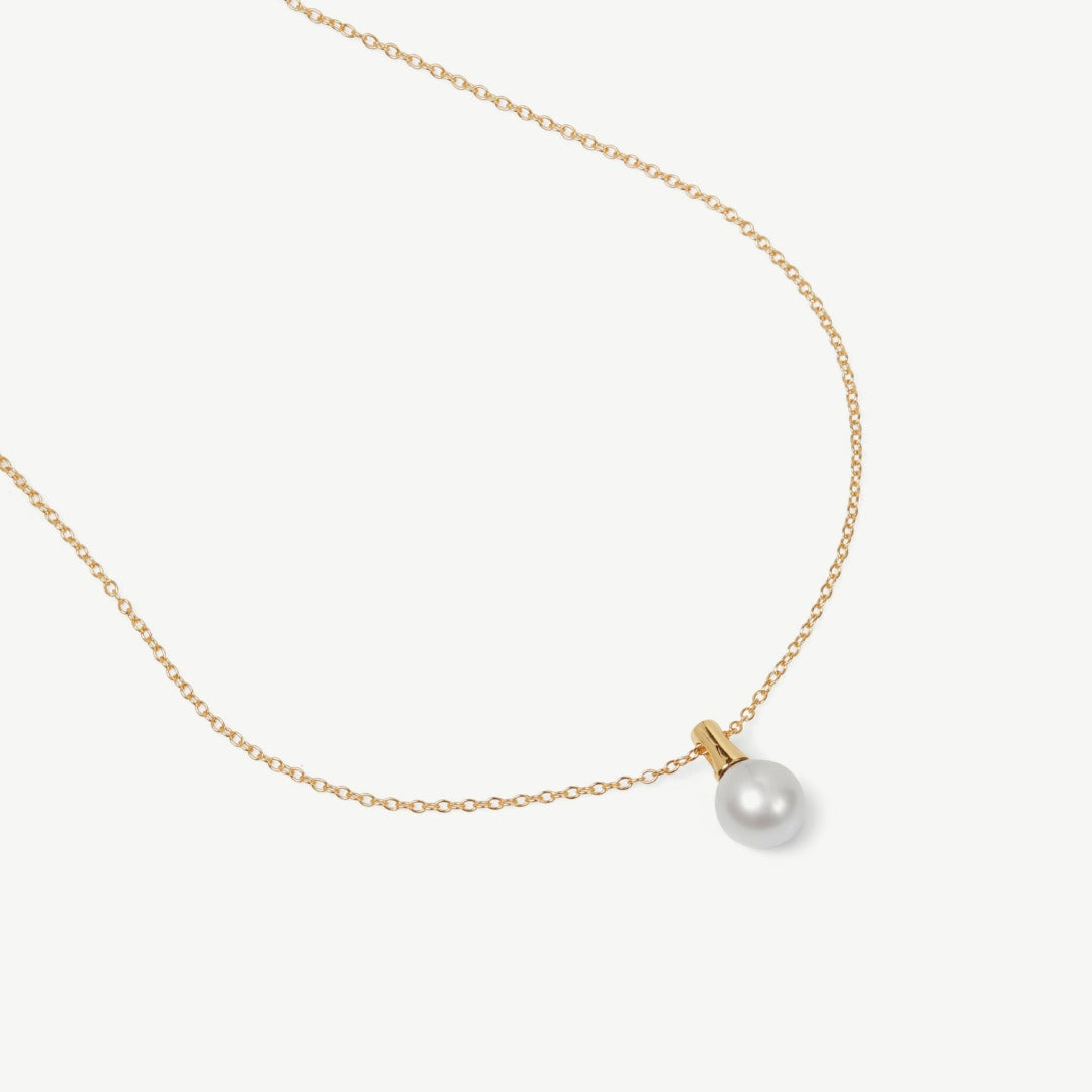 Gold necklace with a single pearl on a white background
