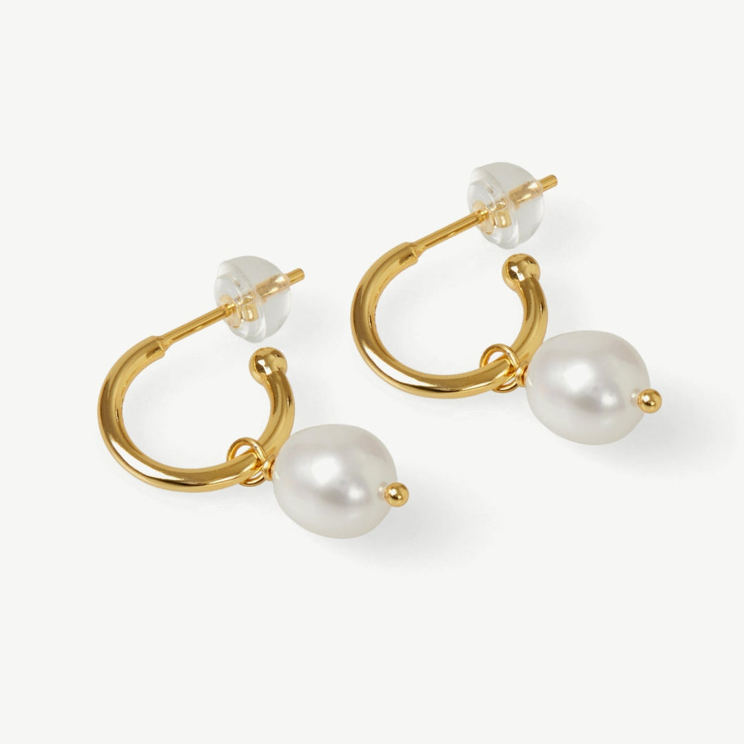 Gold hoop earrings with pearls on a white background
