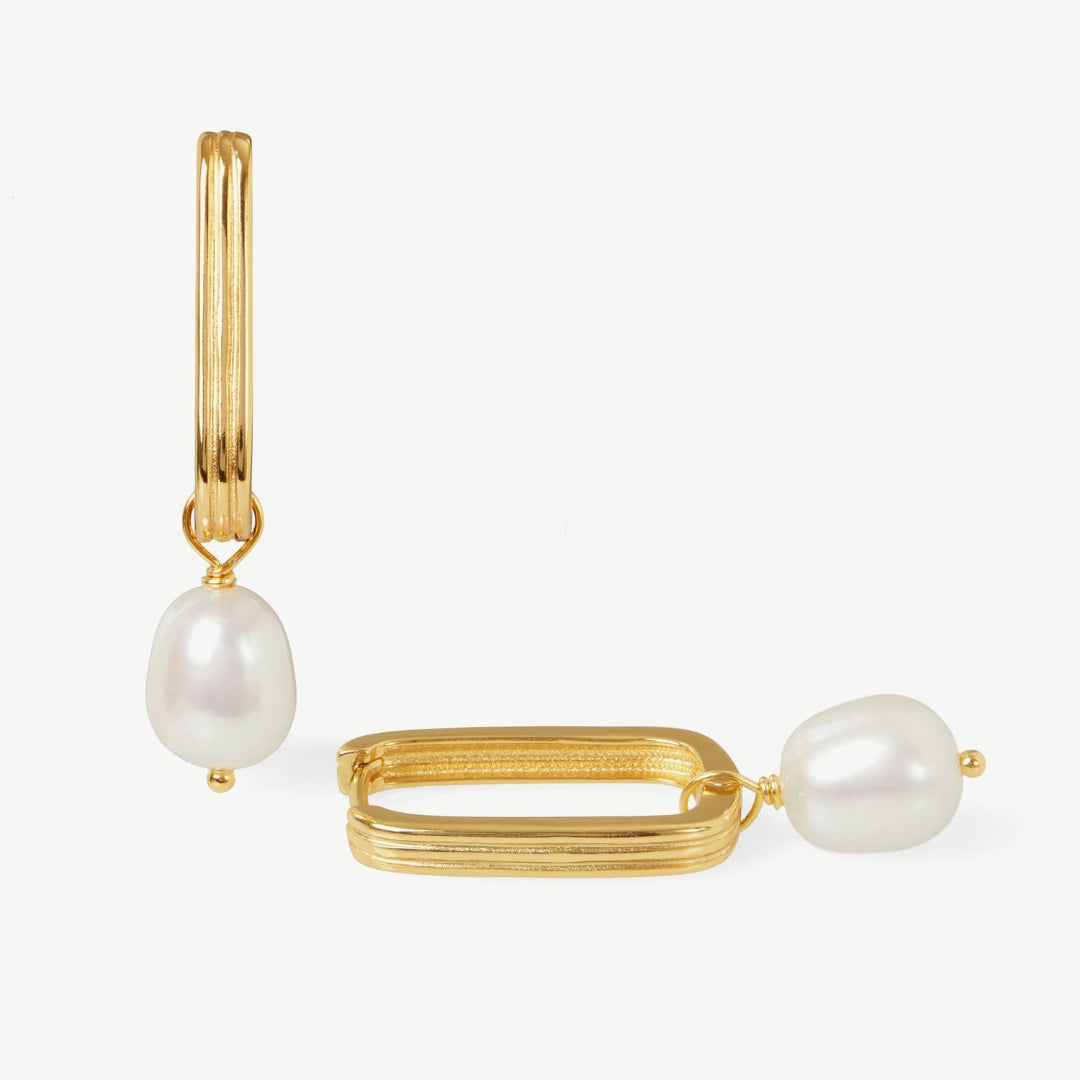 Gold hoop earrings with pearl drops on a white background
