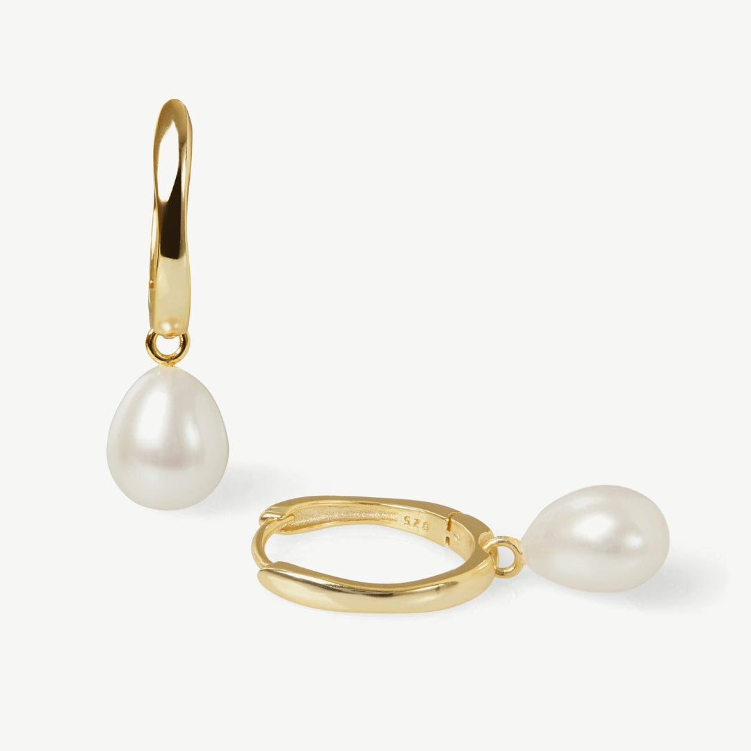 Gold hoop earrings with pearl drops on a white background