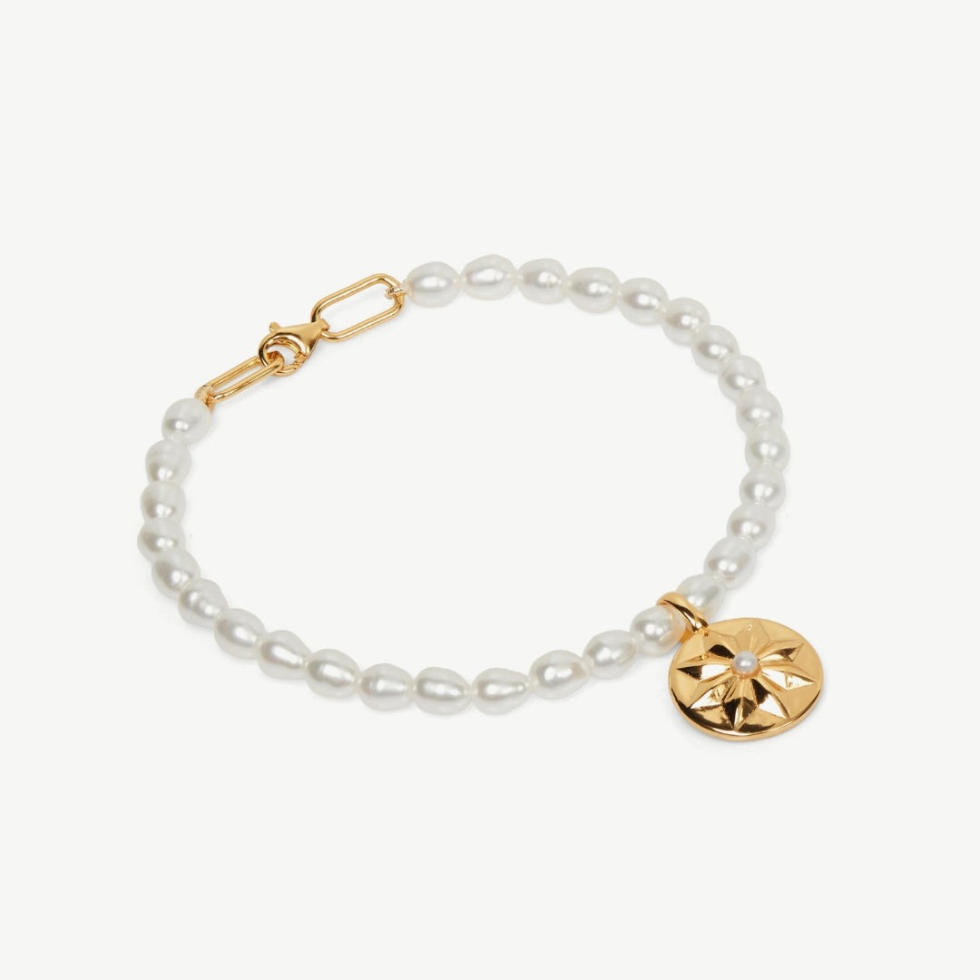 Pearl bracelet with a gold charm on a white background