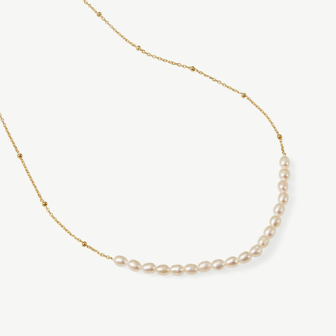 Pearl necklace on a gold chain against a white background