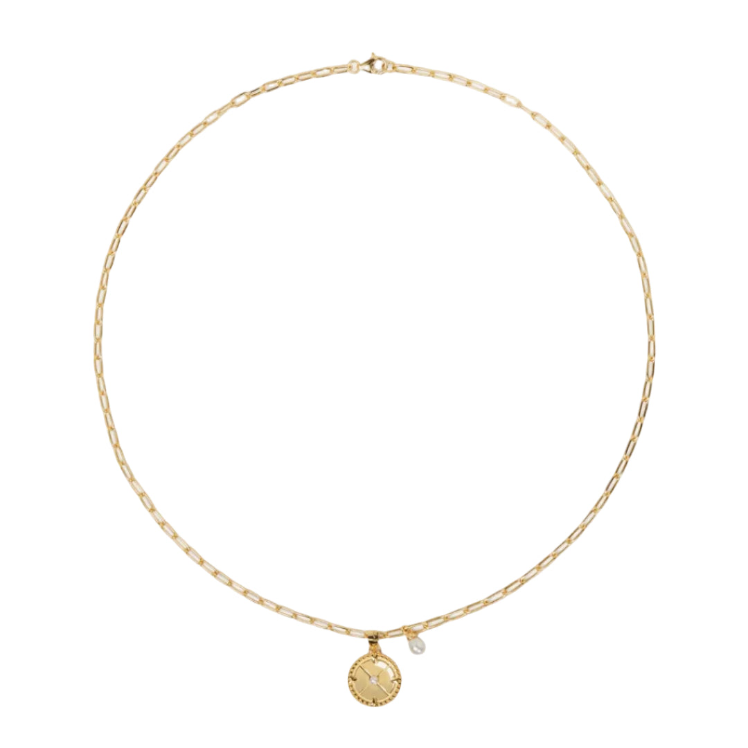 Gold necklace with a pendant on a light beige background