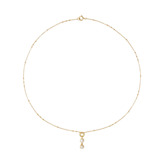 Gold necklace with a small pendant on a light beige background