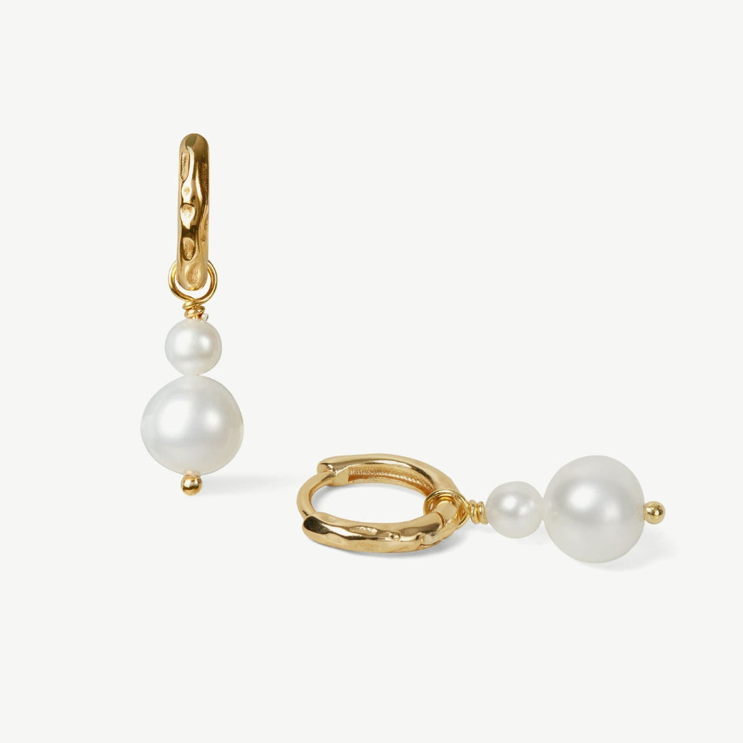 Gold hoop earrings with pearl drops on a white background