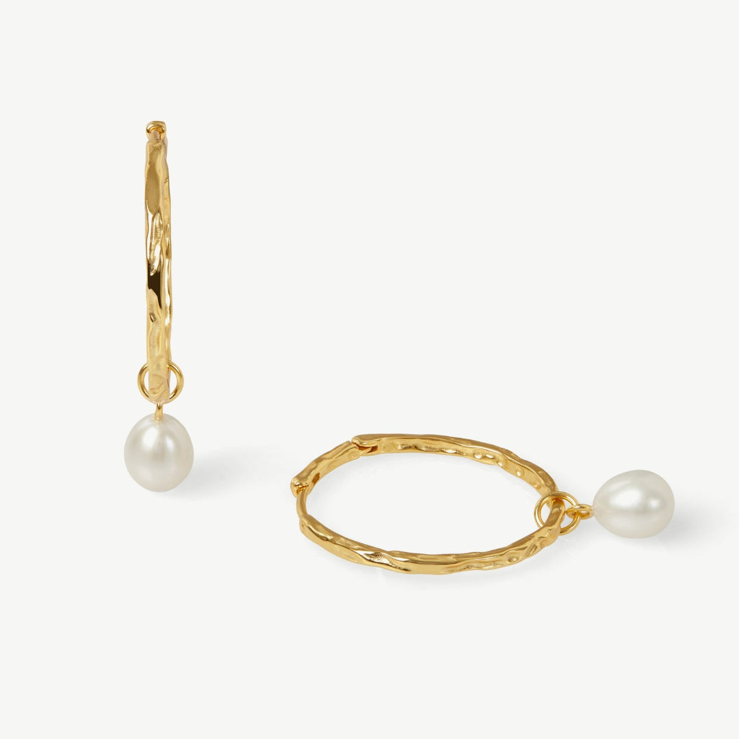 Gold hoop earrings with pearl drops on a white background