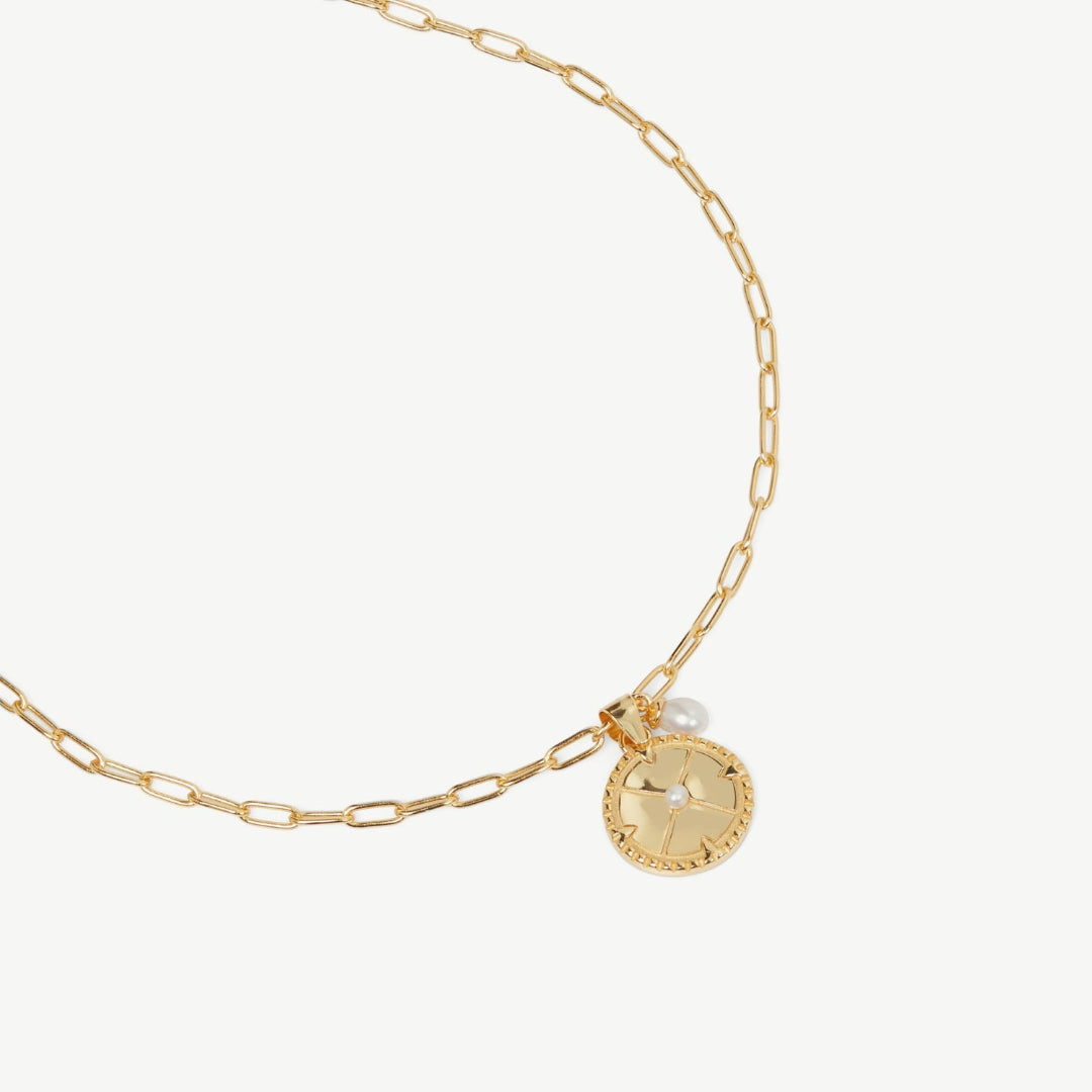 Gold necklace with a round pendant on a white background