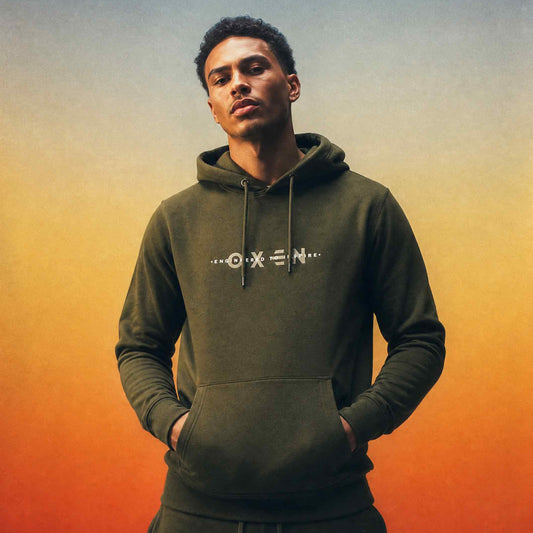 Man wearing a green hoodie with a brand logo against an orange and blue gradient background