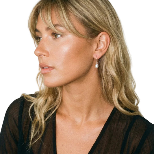 Woman wearing a pearl earring against a plain background