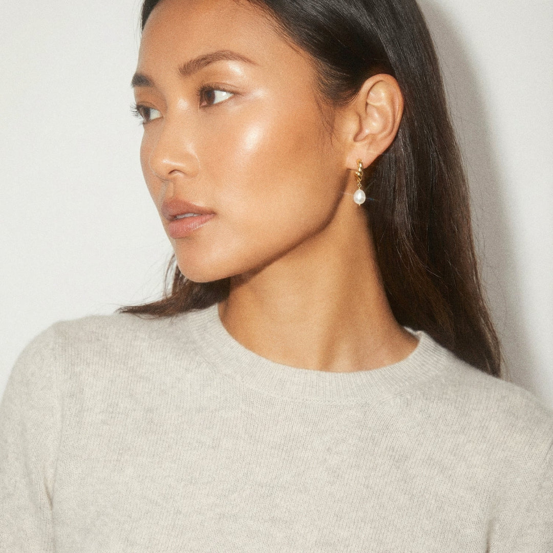 Woman wearing pearl earrings against a plain background