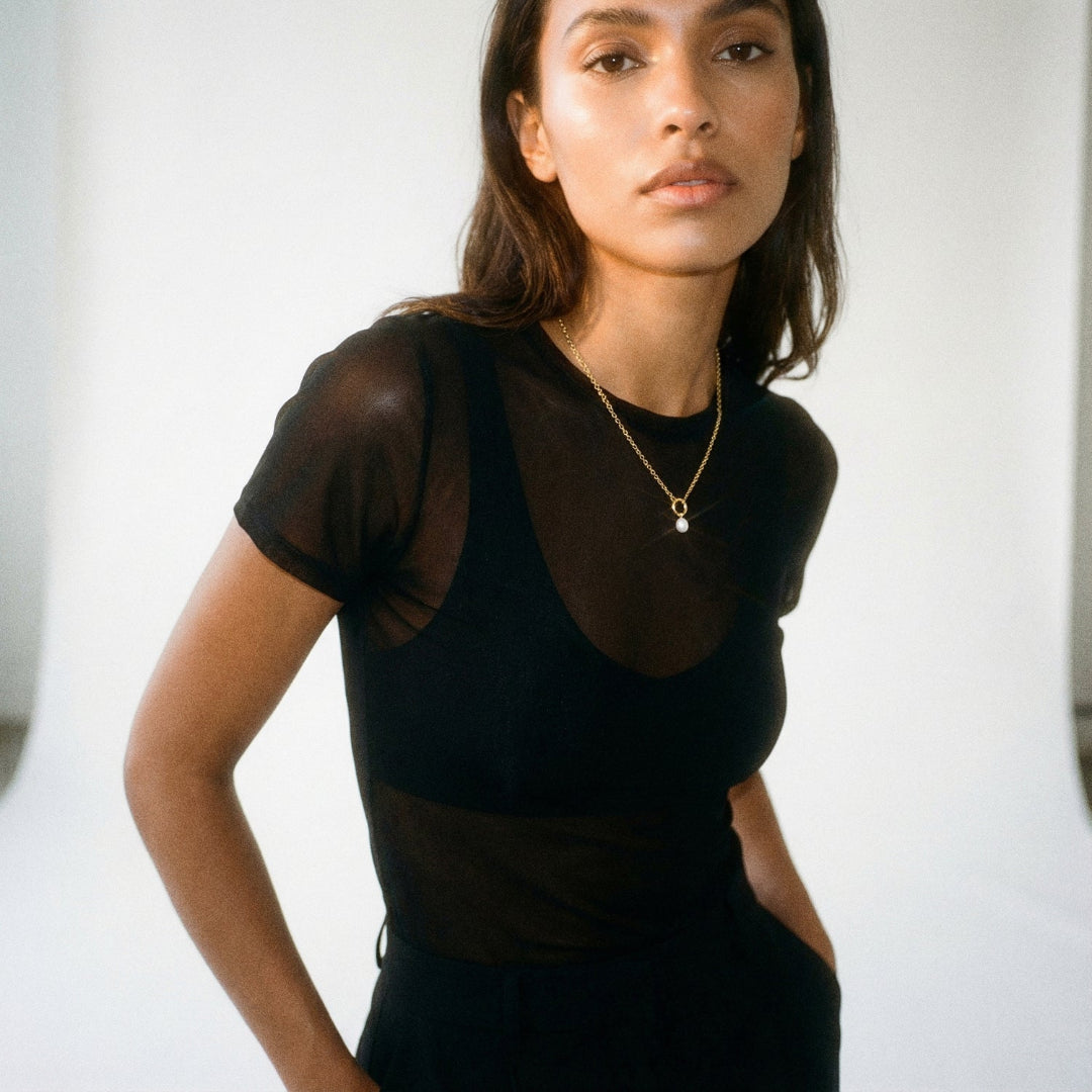 Woman wearing a black sheer top with a white background