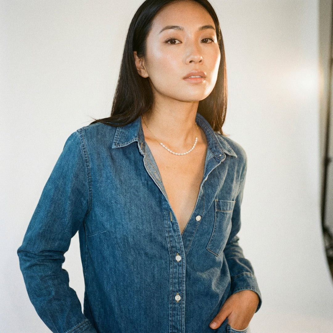 Woman wearing a blue denim shirt against a plain background